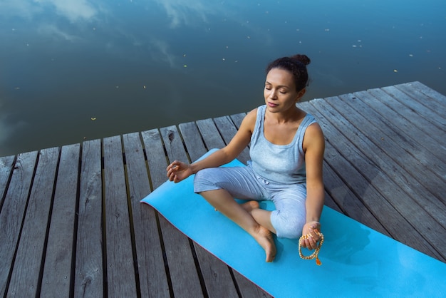 Mujer tyoung haciendo yoga junto al lago