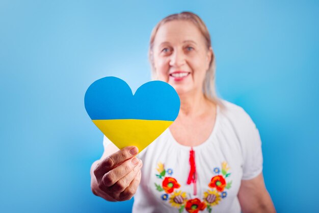 Una mujer ucraniana con una camisa bordada sostiene un corazón de una bandera amarilla y azul para detener la guerra en Ucrania