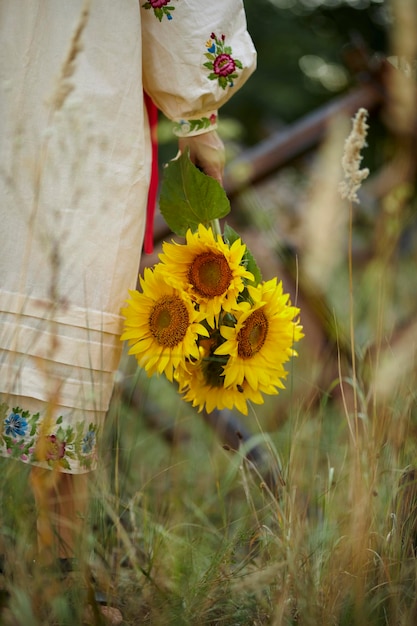 La mujer ucraniana en el vyshyvanka nacional ucraniano sostiene un ramo de girasoles en sus manos.