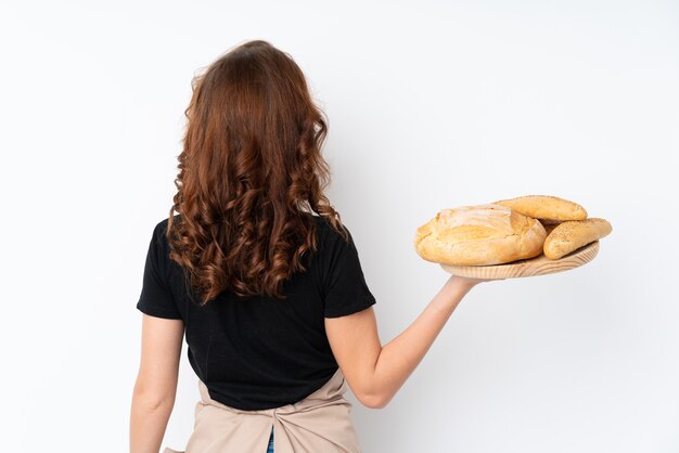 Mujer en uniforme de chef. Panadero de sexo femenino que sostiene una tabla con varios panes en la posición posterior