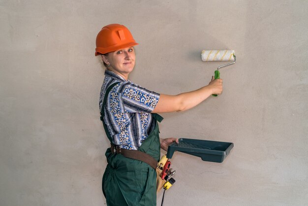 Mujer en uniforme protector con herramientas de pintura