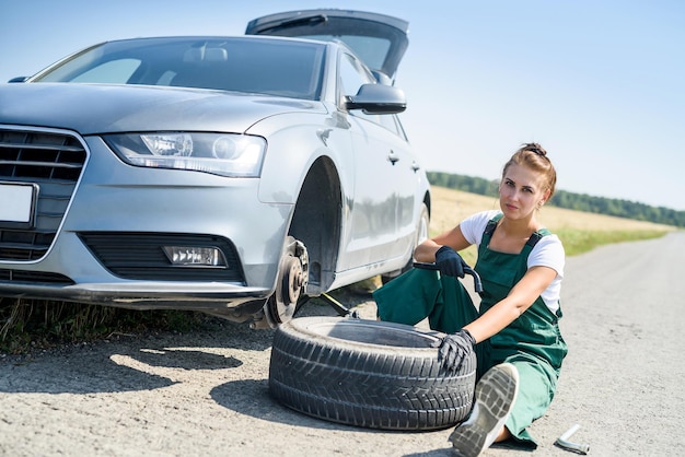 Mujer en uniforme que trabaja para el mantenimiento de los frenos del coche. Reparación de autos. Trabajo de seguridad