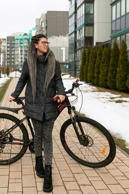 Una mujer urbana bonita con dreadlocks alquiló una bicicleta deportiva para el fin de semana