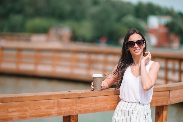 Mujer urbana joven feliz bebiendo café en ciudad europea.