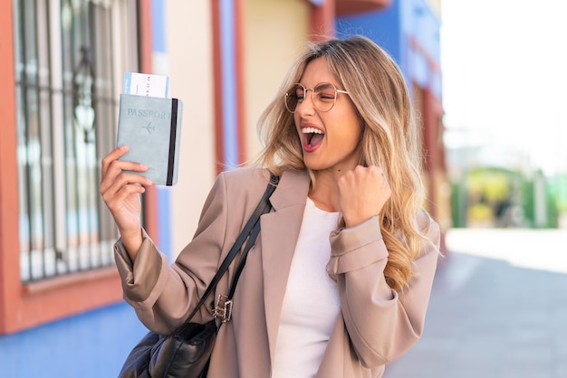 Mujer uruguaya bastante rubia sosteniendo un pasaporte al aire libre celebrando una victoria