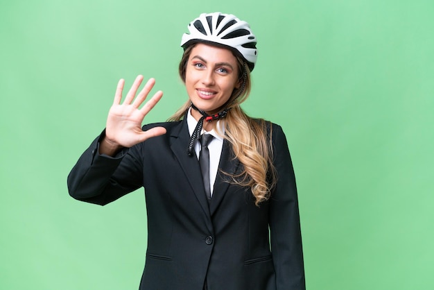 Mujer uruguaya de negocios que lleva un casco de motociclista sobre un fondo aislado contando cinco con los dedos