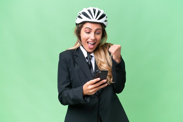 Mujer uruguaya de negocios que lleva un casco de motociclista sobre un fondo aislado sorprendida y enviando un mensaje