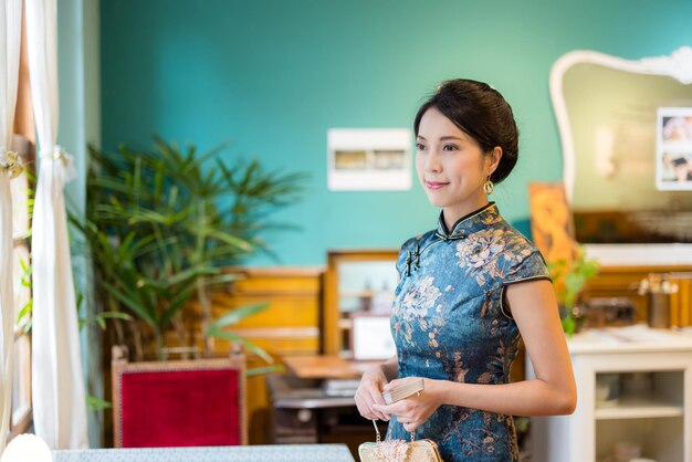 La mujer usa cheongsam en la casa de té vintage