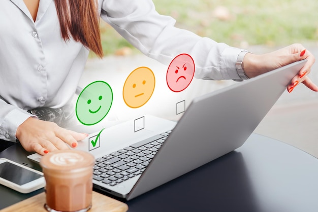 Foto la mujer usa la computadora portátil eligiendo el concepto de salud mental del icono de la cara de sonrisa feliz verde