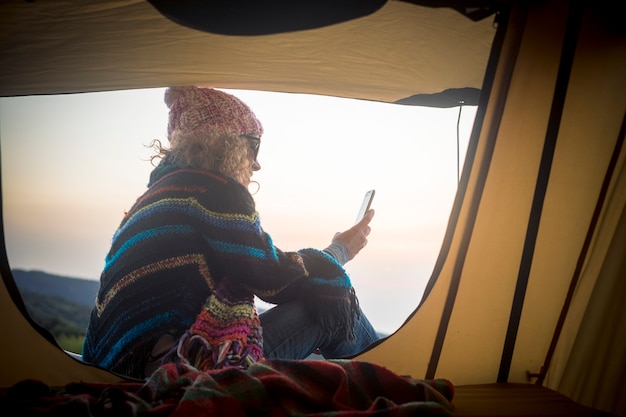 La mujer usa la conexión a Internet y el teléfono móvil fuera de la tienda en la naturaleza