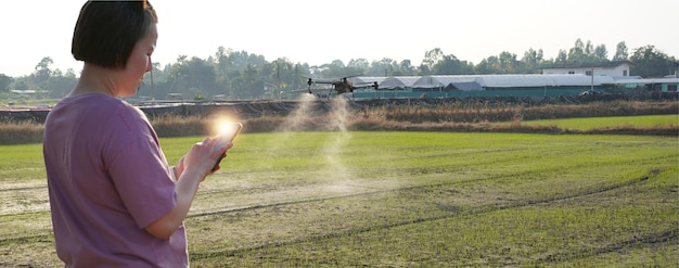 Foto mujer usa drones para rociar hormonas en el campo de cosecha