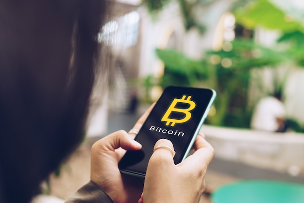 Mujer usa gadget móvil smartphone gana dinero online compra bitcoin con icono de signo emergente.