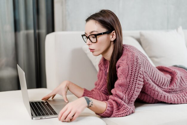 Mujer usa laptop en casa en un sofá