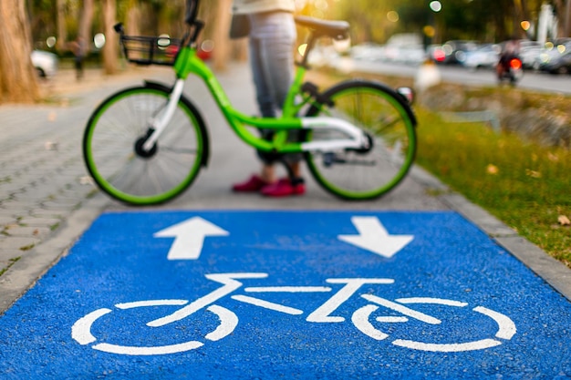 Foto una mujer usa una marca quirúrgica para andar en bicicleta en un carril bici con señales de bicicletas en un parque público durante la nueva pandemia normal de coronavirus covid19