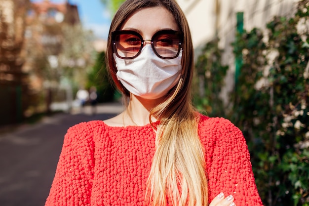 La mujer usa una máscara protectora hecha a mano al aire libre durante la pandemia de coronavirus covid-19