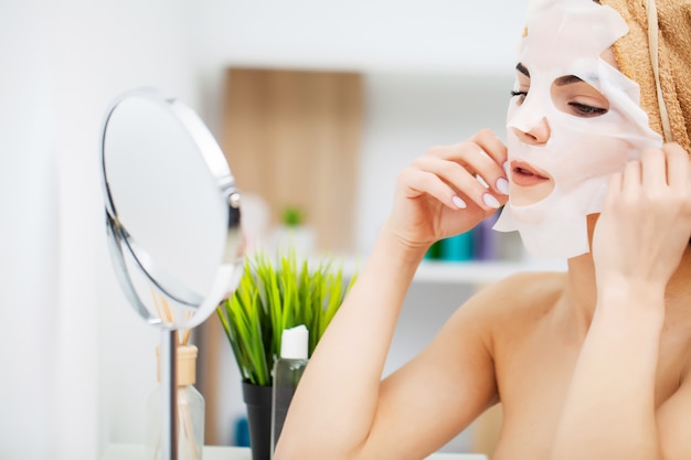 Una mujer usa una mascarilla facial en el baño