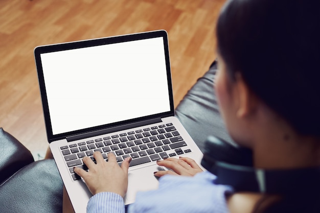 la mujer usa una pantalla de computadora portátil vacía en una habitación en un sofá negro y usa auriculares negros.