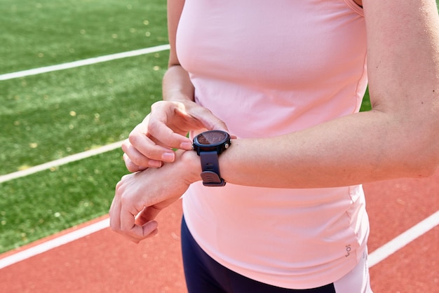 La mujer usa un reloj inteligente de fitness comprobando los resultados después del entrenamiento deportivo