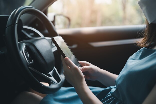 La mujer usa su teléfono móvil para mirar el mapa mientras viaja en automóvil La mujer llama al seguro o a alguien para que la ayude cuando el automóvil se descompone o tiene un accidente