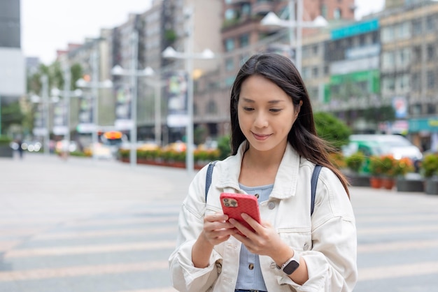 Mujer usa teléfono inteligente en la calle