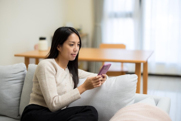 La mujer usa el teléfono móvil en casa