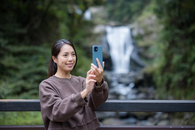 Mujer usa teléfono móvil para hacerse una selfie en el bosque