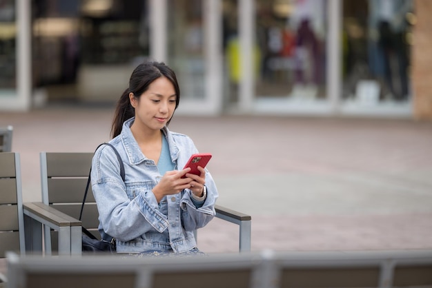 La mujer usa el teléfono móvil y se sienta en un café al aire libre