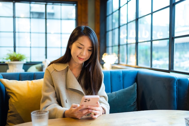 La mujer usa el teléfono móvil y se sienta dentro del restaurante.