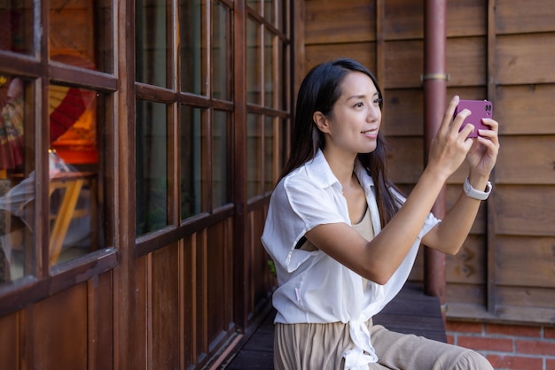 Mujer usa teléfono móvil para tomar fotos en una casa de madera japonesa