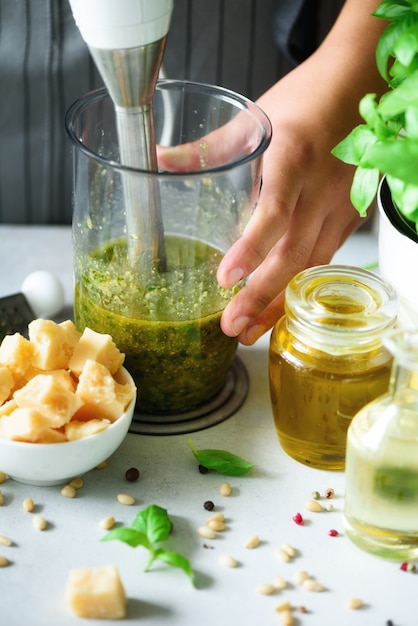 Mujer usando batidora de mano para hacer pesto.