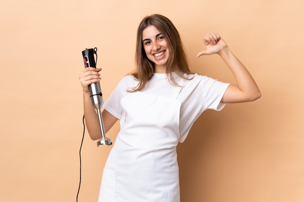 Mujer usando batidora de mano orgullosa y satisfecha