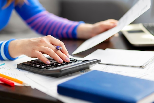 Mujer usando calculadora para calcular las finanzas del hogar o los impuestos del automóvil