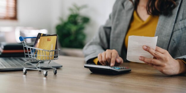 Mujer usando calculadora sosteniendo facturas de papel calculando gastos de planificación pagos de dinero concepto manos femeninas contando datos impuestos de IVA costo haciendo papeleo en casa