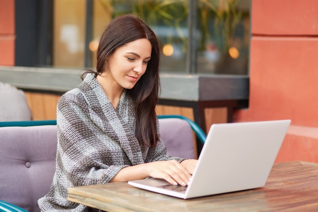 Mujer usando la computadora portátil en el café