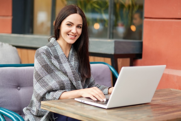 Mujer usando la computadora portátil en el café