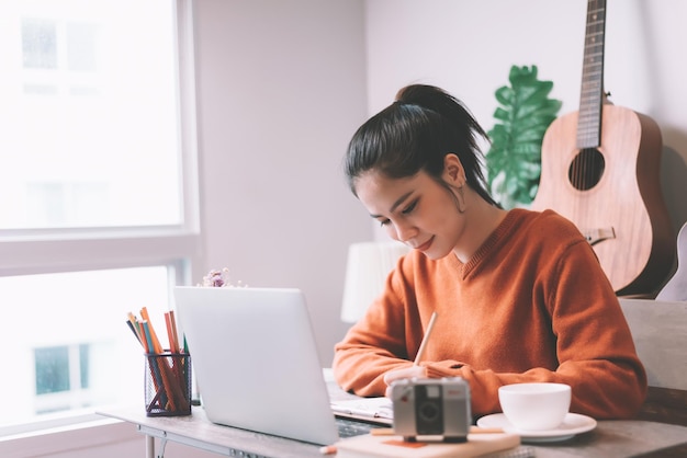 Mujer usando una computadora portátil mientras está sentada en la mesa