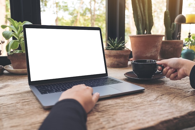 mujer usando y escribiendo en la computadora portátil con pantalla de escritorio en blanco blanco sobre mesa de madera vintage