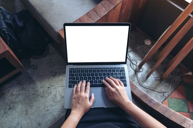 Mujer usando y escribiendo en una computadora portátil con pantalla de escritorio en blanco en blanco