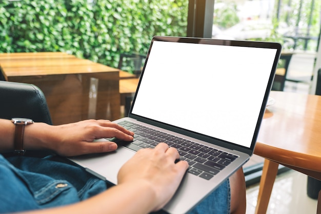 Una mujer usando y escribiendo en el teclado del ordenador portátil con una pantalla de escritorio en blanco