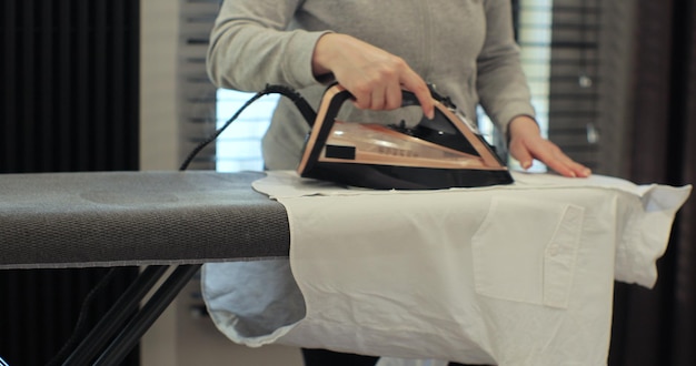 Foto mujer usando hierro con modo de vapor para ropa arrugada hogar rutina de limpieza doméstica