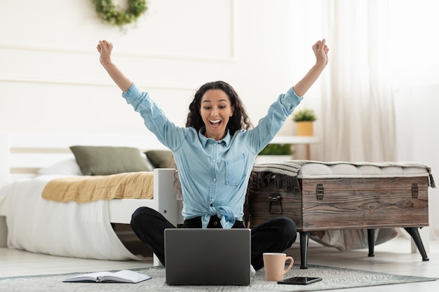 Mujer usando laptop celebrando el éxito agitando los puños gritando sí