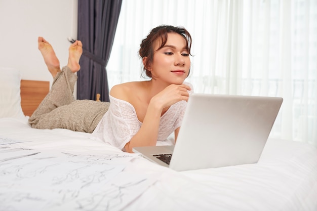 Mujer usando laptop en dormitorio