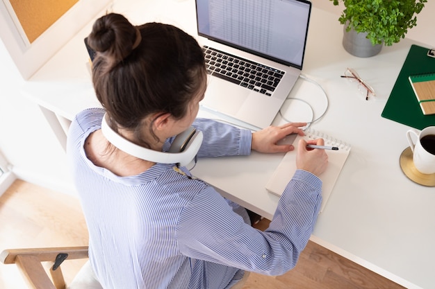 Foto mujer usando laptop, lugar de trabajo en estilo moderno. comunicación y teletrabajo. distancia social