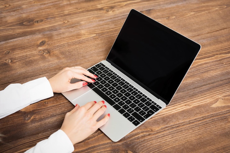 Foto mujer usando laptop en mesa de madera