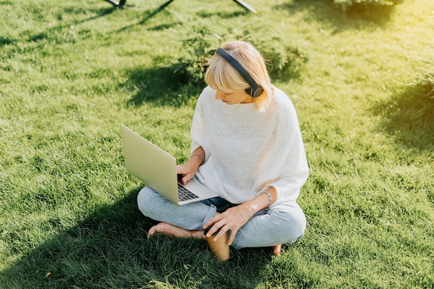 Mujer usando laptop sentada en la hierba