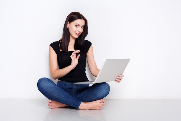 Mujer usando laptop sentada en el piso del estudio