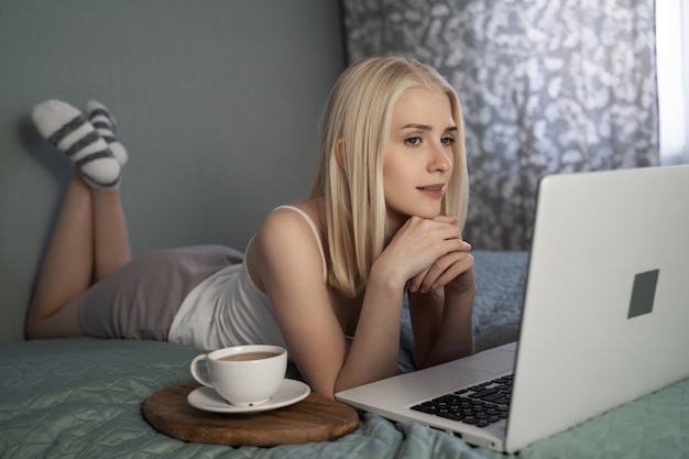 Mujer usando laptop en su cama.