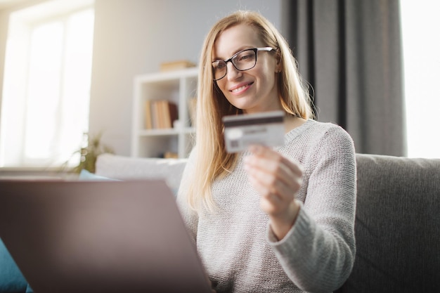 Mujer usando laptop y tarjeta de crédito para compras en línea