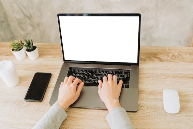 Mujer usando laptop y trabajando en mesa de madera