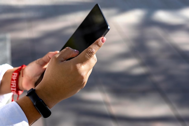 Mujer usando y mostrando una pantalla de tableta en blanco en la calle frente a una tienda